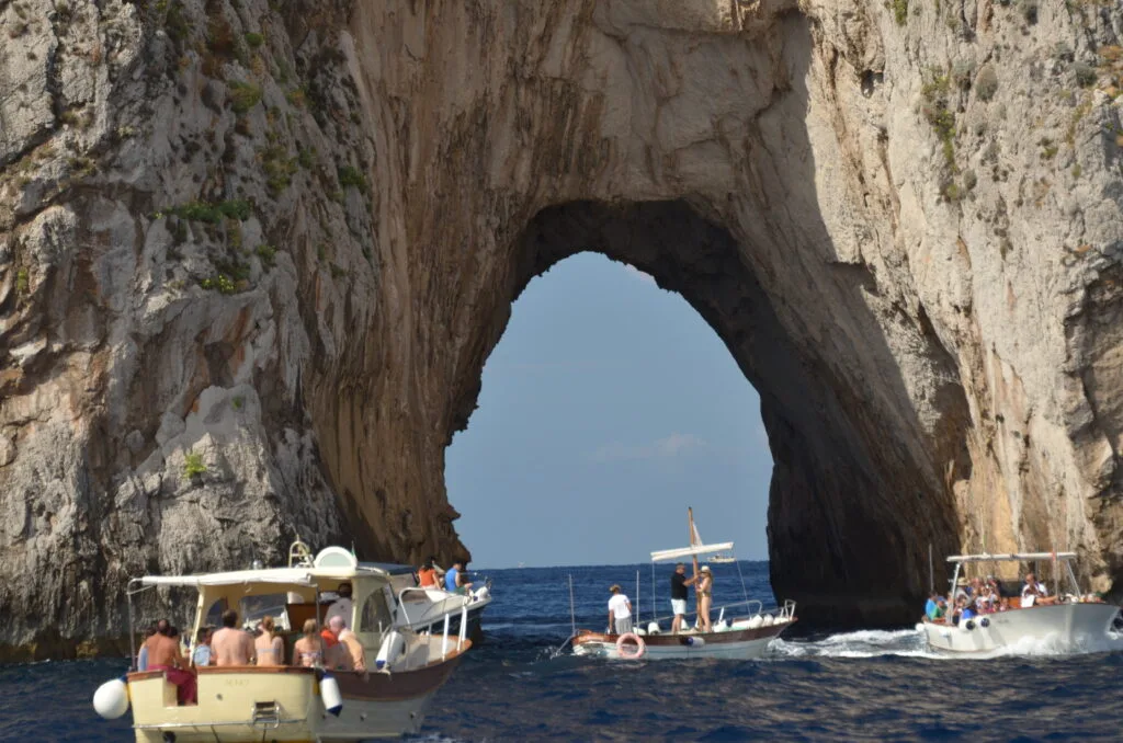 Boats are taking tourists to large arches created by erosion of stones over the years around the island of Capri.