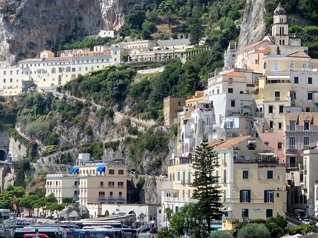 A village that clings to the cliffs of Amalfi Coast Italy with levels of homes and a steep winding street down to the water.
