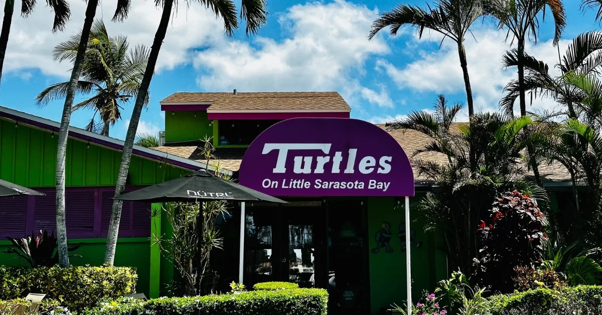 A purple sign for Turtles. Restaurant. The wooden traditional building is painted green.