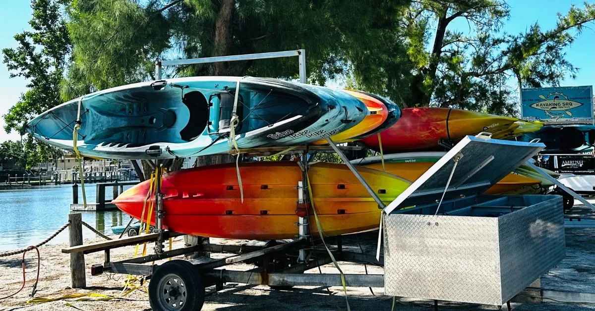 Rack of multi coloured kayaks for rent next to a lagoon.