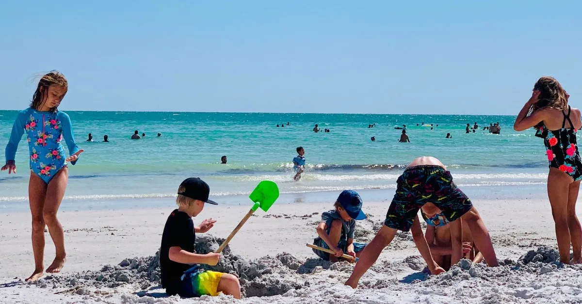 Children digging in the sand on Siesta Key Beach Florida.
