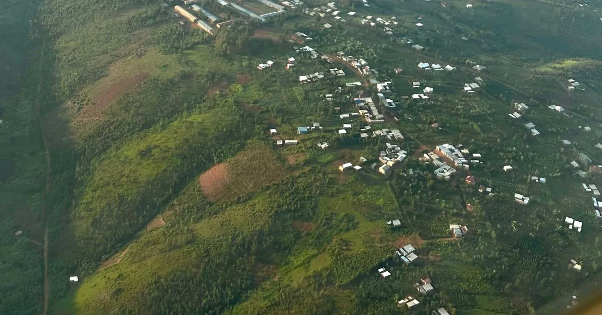 Aerial view descending into Kigali shows small homes and patchwork fields.