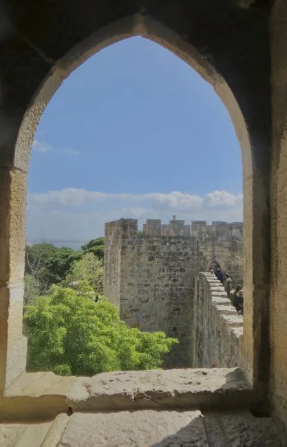 Views in Lisbon through an arch way to an old stone castle wall.