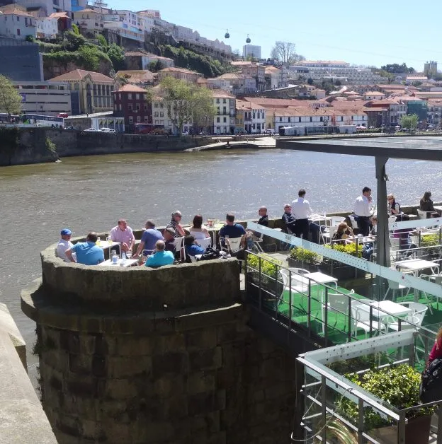 People enjoying refreshments on a balcony overlooking the Douro River.