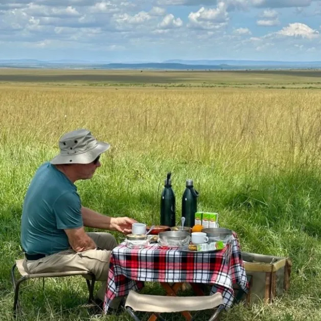 Man having picnic in Masai Mara grassland area.