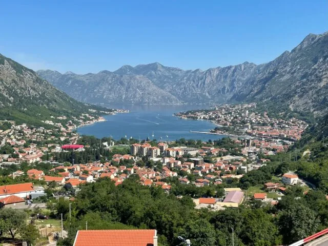 Panoramic view of the Bay of Kotor in Montenegro, with red-roofed coastal towns, blue Adriatic waters, and dramatic mountain scenery, a highlight on a Montenegro and Northern Albania itinerary.