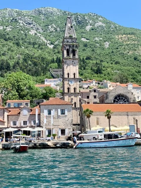 A church steeple and surrounding buildings next to the bay in Perast Montenegro.