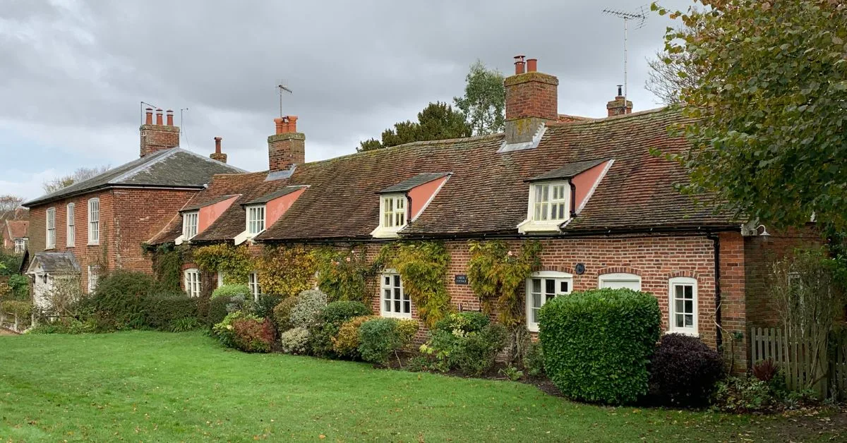 Row of country cottages with red brick and shrubs around them