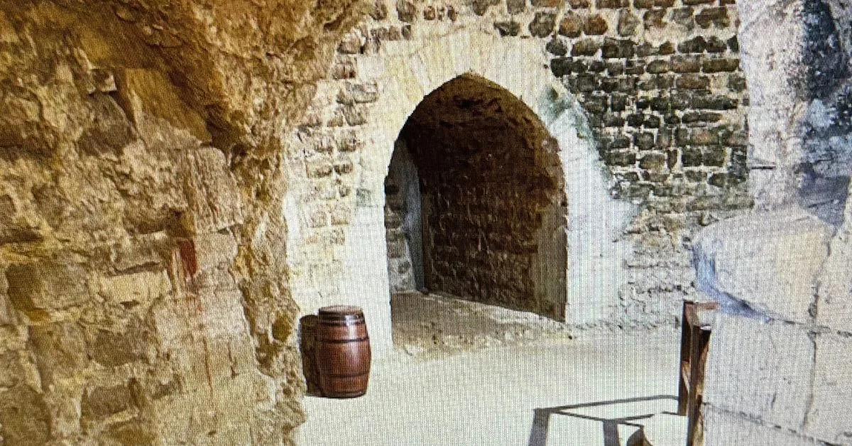 Lower floor in Orford Castle showing an stone archway with open fireplace and a small brown barrel to the left of the arch