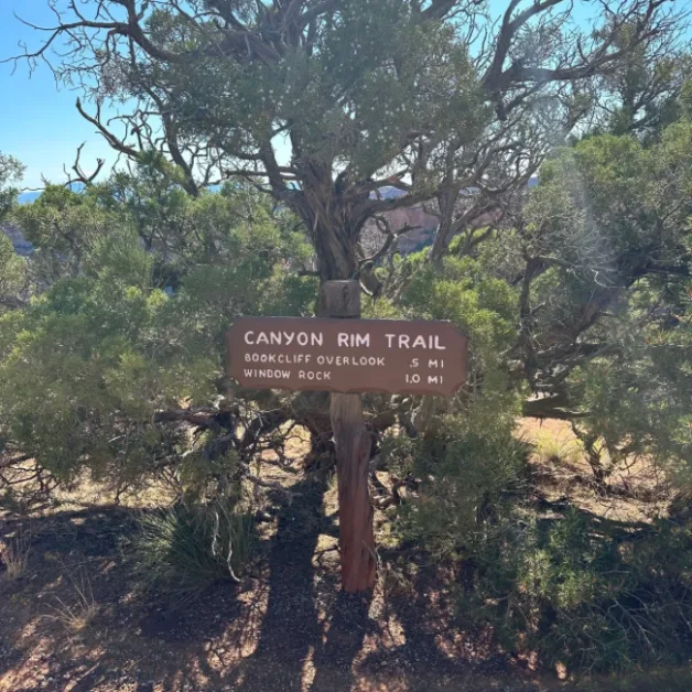 A sign in Colorado National Monument Park with hikes and distances on it.