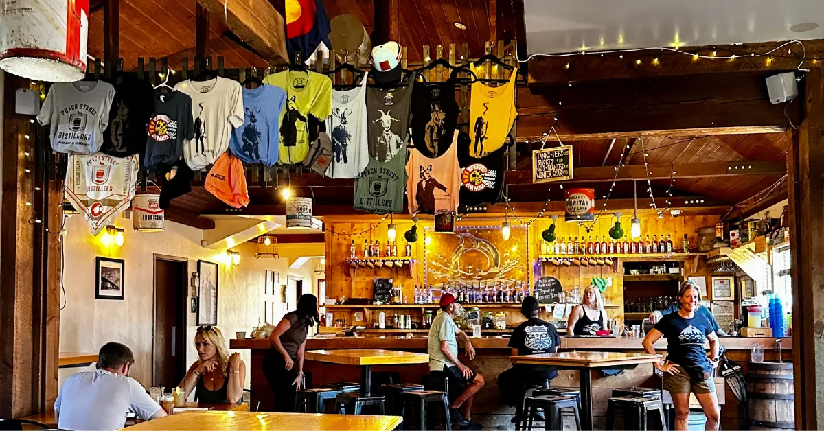 Peach Street Distillers interior with a large bar area and t-shirts for sale hanging from the roof.