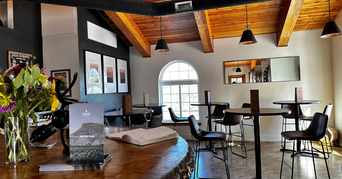 A Bar with wine menu and tables with seats for guests.