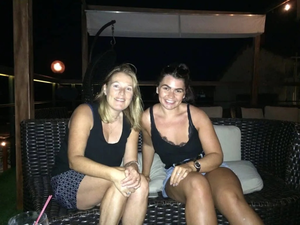 Two women sitting on a rooftop open air bar terrace on a sofa in Panama City.