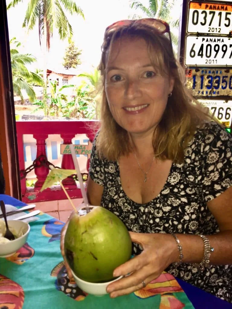 Woman has a cocktail served in the shell of a green coconut.