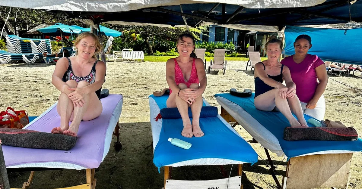 Women sitting on massage tables on Tamarindo Beach.