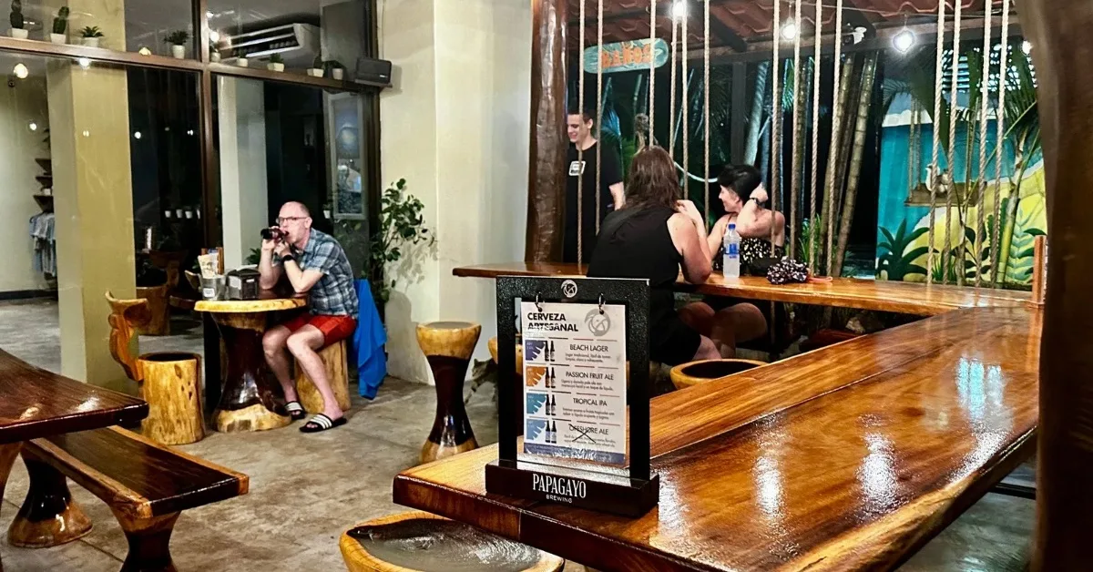 People sitting at swing tables hung by ropes from the ceiling in a restaurant Tamarindo Costa Rica.