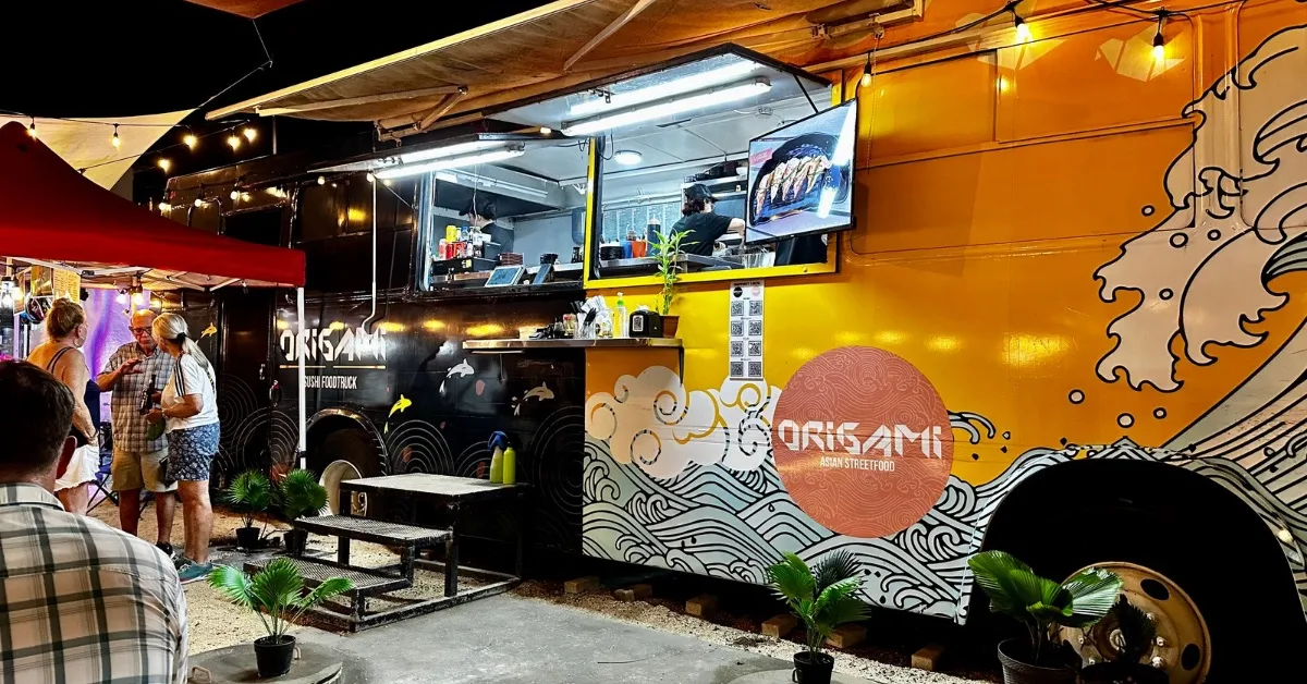 A brightly painted food truck within an outdoor market.