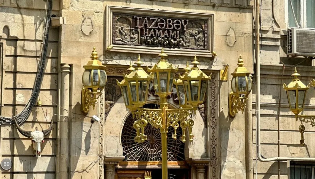 Entrance to one of the Hamman Baths in Baku, Azerbaijan with ancient signage above the brick entry way and gold lamps.