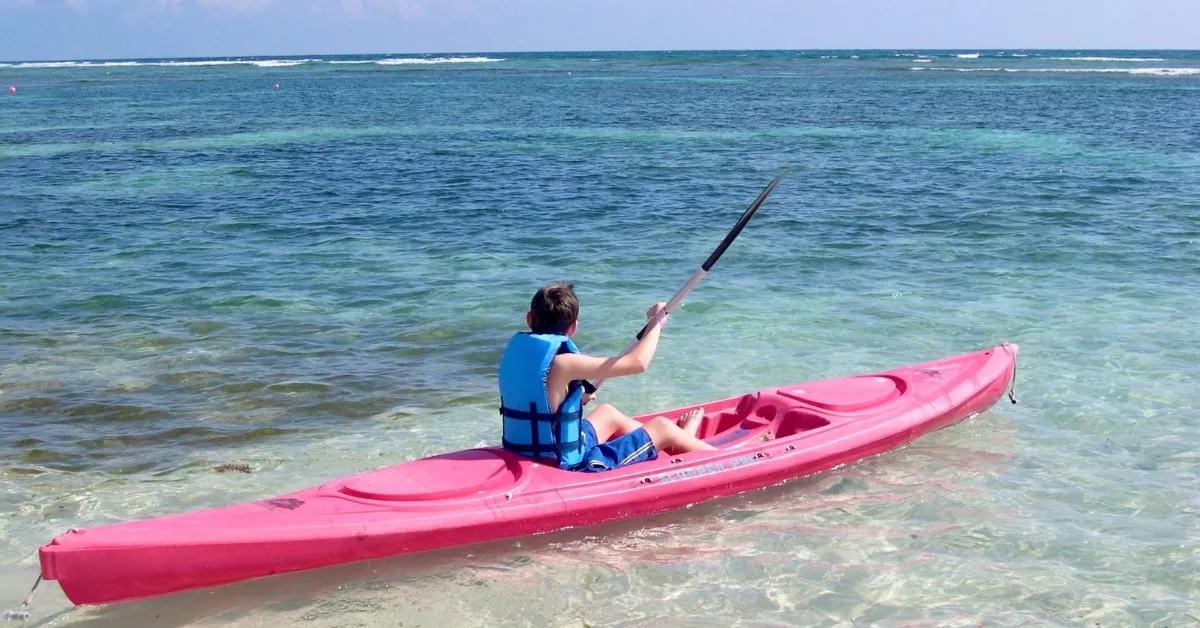 Child kayaking in shallow water.