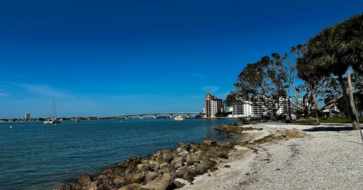 A stretch of coastal Sarasota with rocks and the bay stretching over to Ringling Bridge to Lido Key.