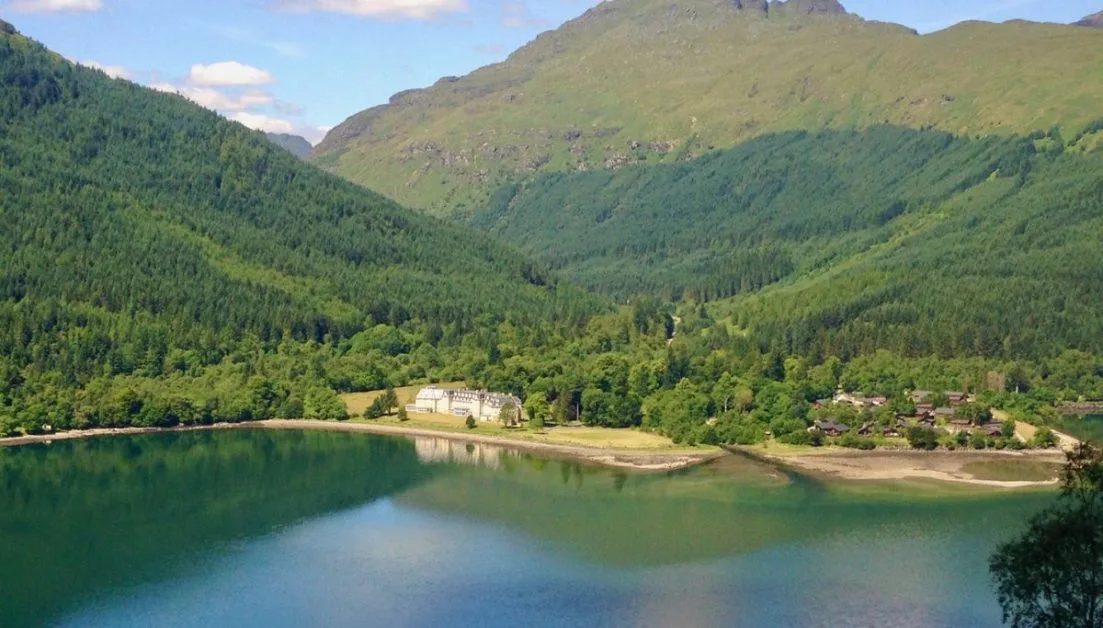 Views of Scotland lochs and hill with homes in a valley next to the water.
