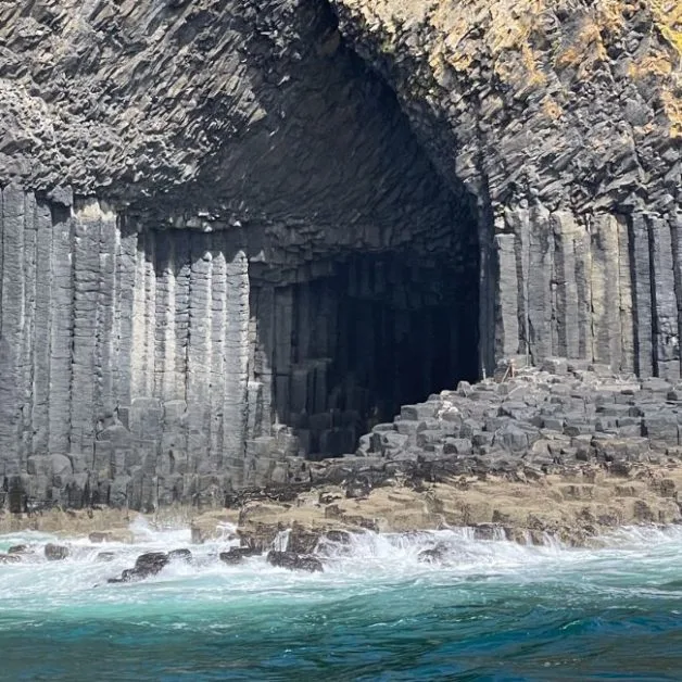 Staffa basalt cave entrance, an island off Scotland's west coast. Waves lap up against the basalt rock upthrusts.