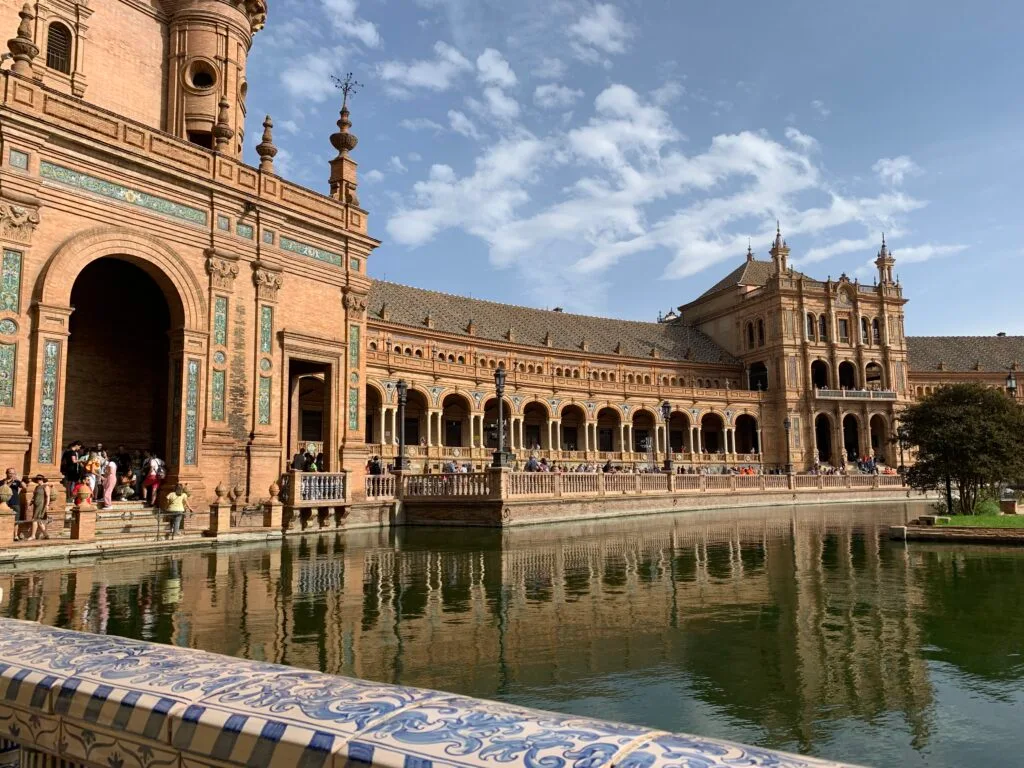 A large pond in front of a palace building with mosaic tile decor.