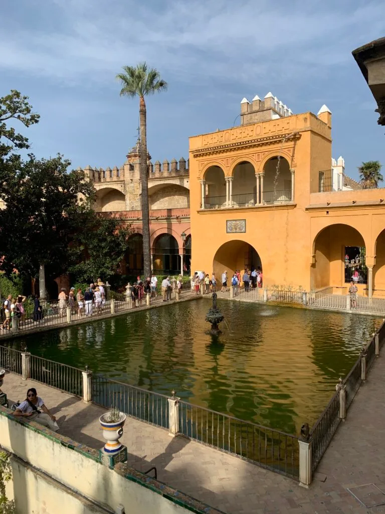 Sun rays hit the side of the palace of Alcazar ponds and fountains.