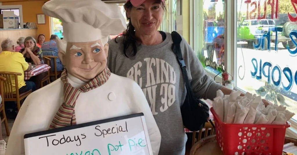 Woman in Biscuit Barn traditional restaurant in Crystal River standing next to a menu board.