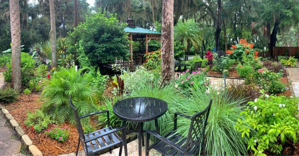 An outdoor patio table and chairs in a guest garden with a gazebo at Crystal River Retreat hotel.