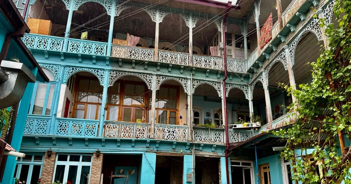 Old Town Tbilisi multiple housing with blue exterior and wrought iron archways into each room.