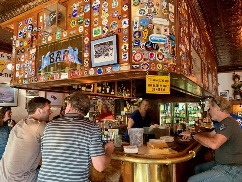 F Street Station Bar in Anchorage with people sitting at the bar. A large slab of cheese sits on the counter for customers to enjoy.
