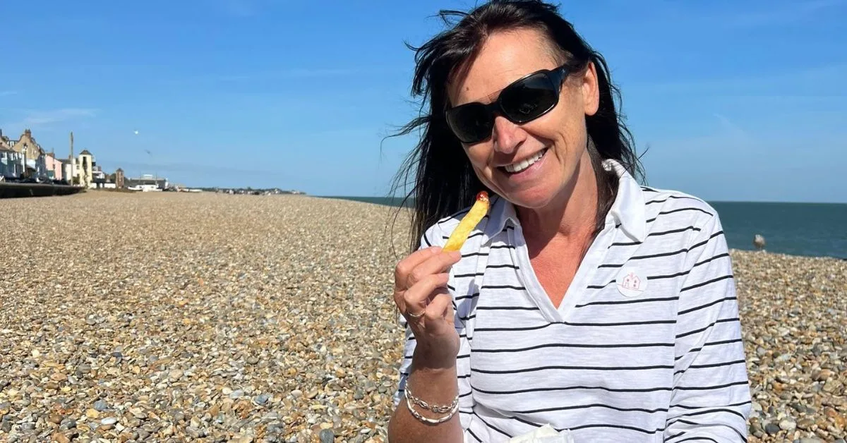 Woman standing on a beach - one of the most popular things to do in Aldeburgh. The beach is wide with shingle and pebbles.