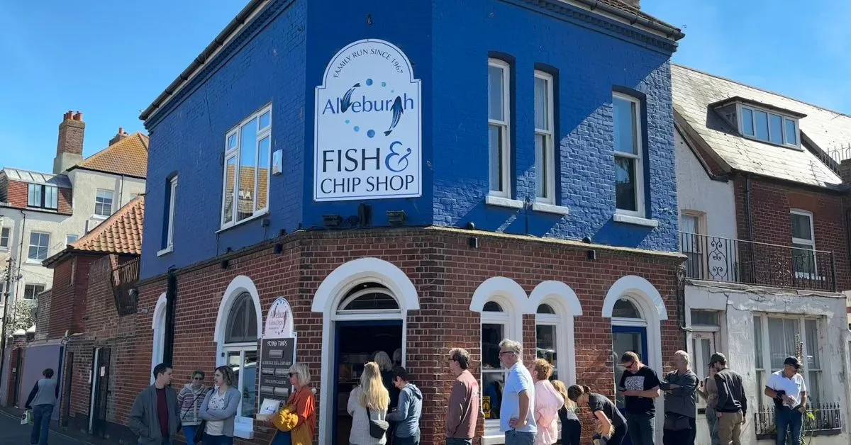 People are lined up outside a fish and chip shop in Aldeburgh Suffolk.