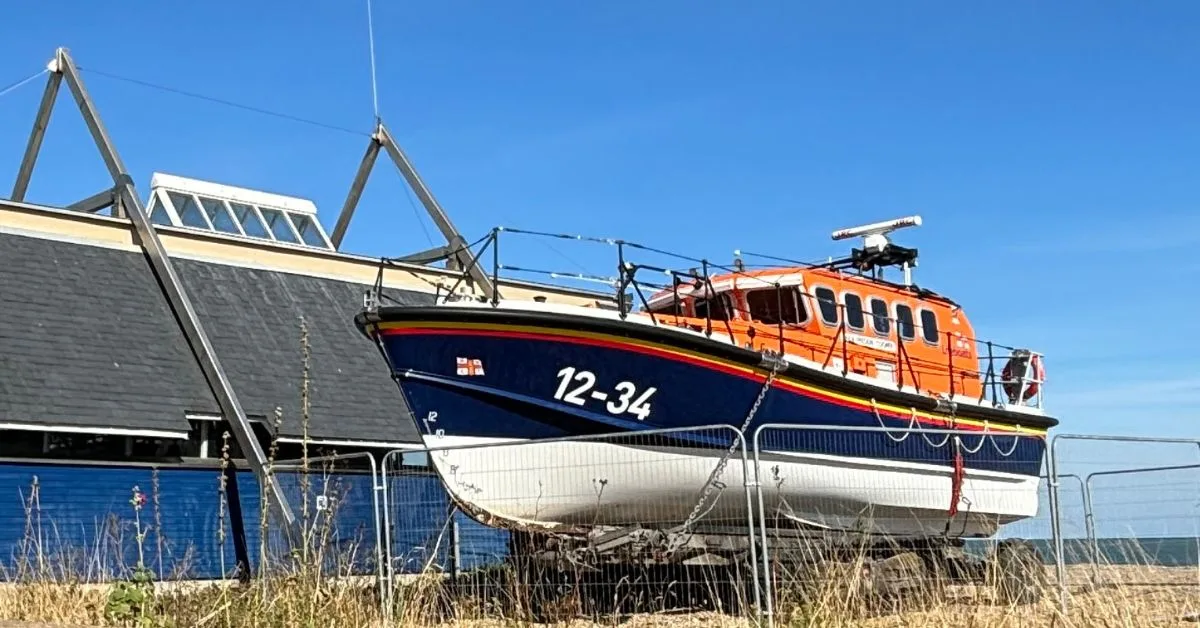 An orange and blue lifeboat sits outside the Lifeboat Stations. One of the fun things to do in Aldeburgh is to visit this local station.