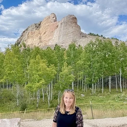Woman standing in a viewing area in front of a popular Black Hills Mountain Carving revealing the head of an ancient leader.