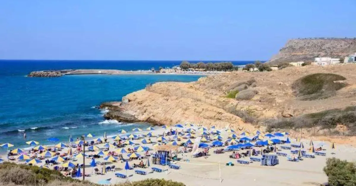 Umbrellas lined up on Sissi Beach Crete.  Next to the beach are rocky headlands.