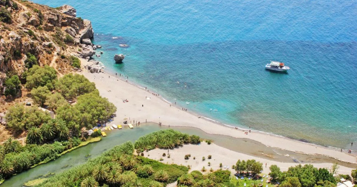 A river flows into the sea on Crete. A small boat is anchored just offshore.