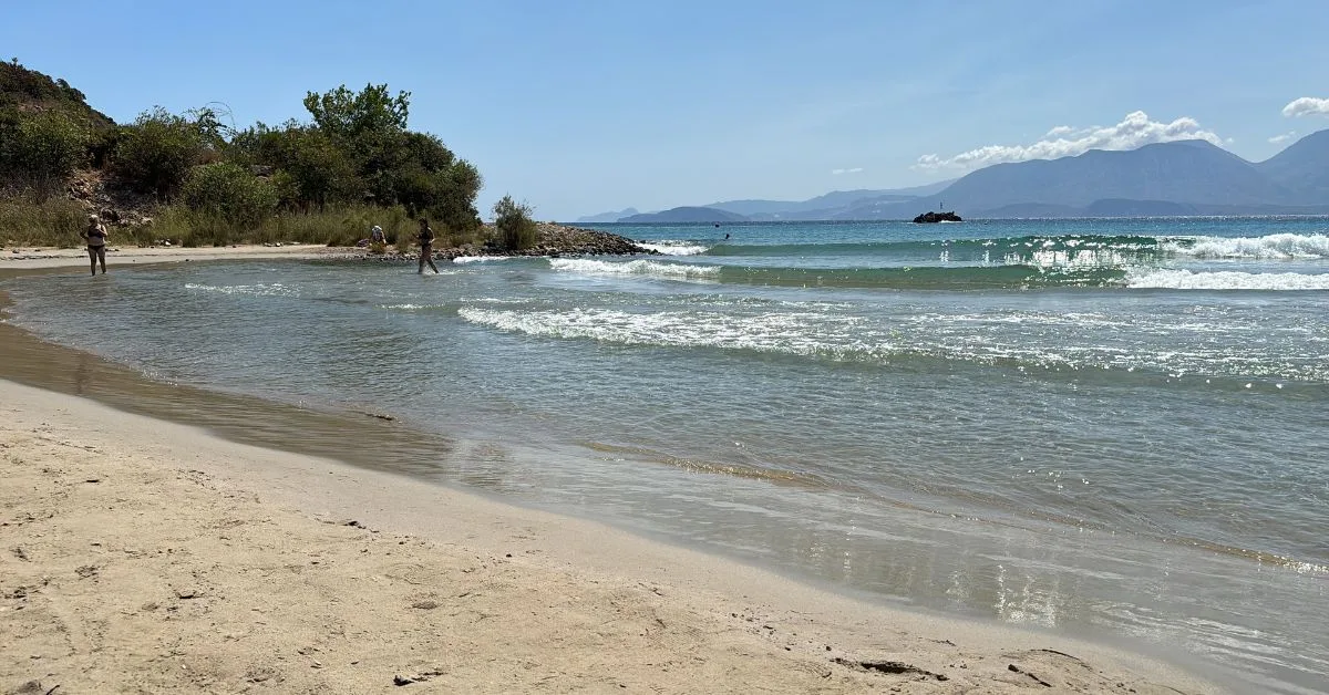 A quiet sandy beach with people enjoying the water in Crete.