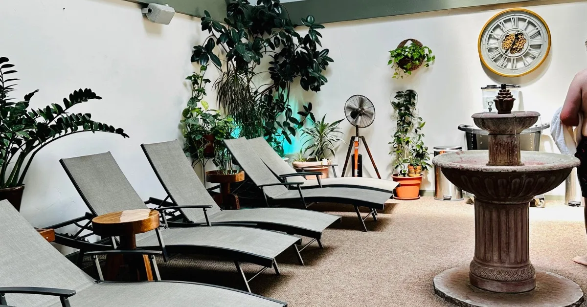 Relaxation area with lounger chairs and green plants at a spa.