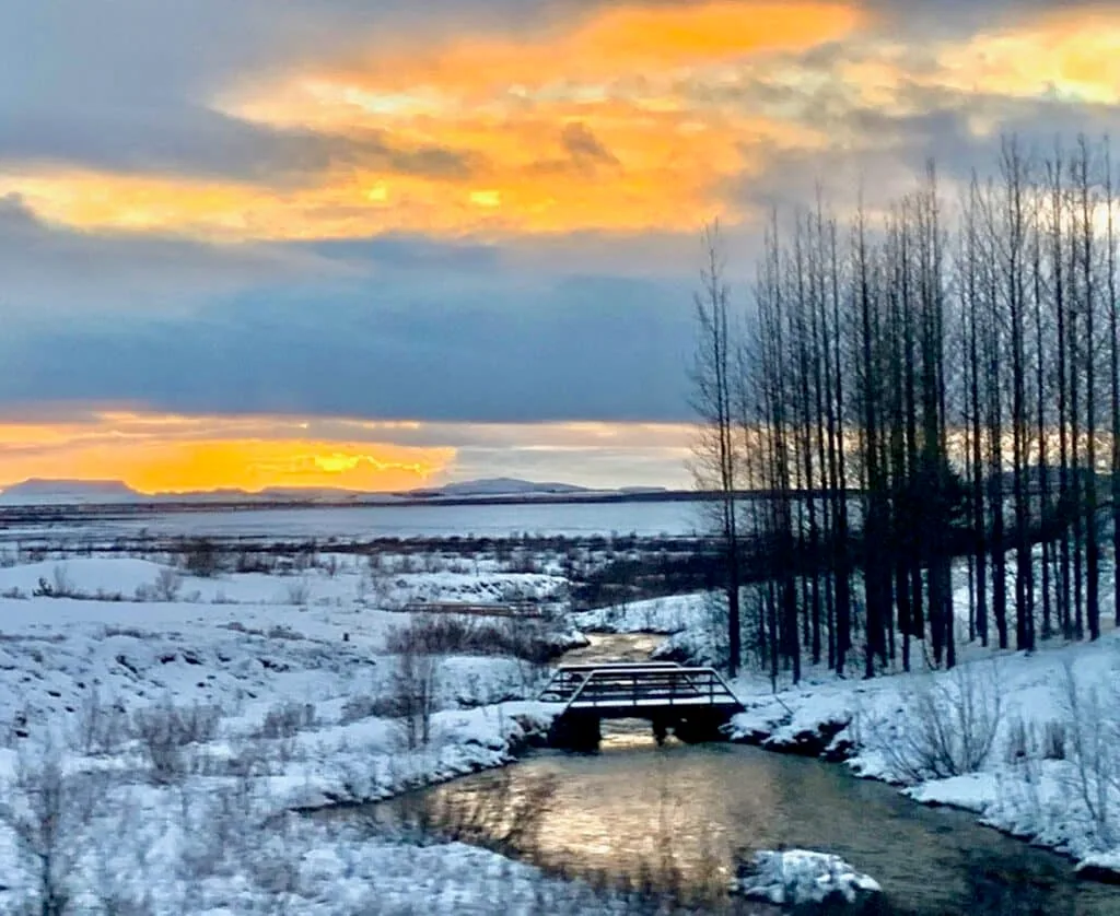 Landscape in Iceland in Winter with snow on the river and sun setting behind some clouds.