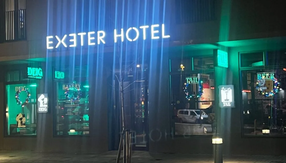 Exeter Hotel entrance with green and blue night lights illuminating the building.