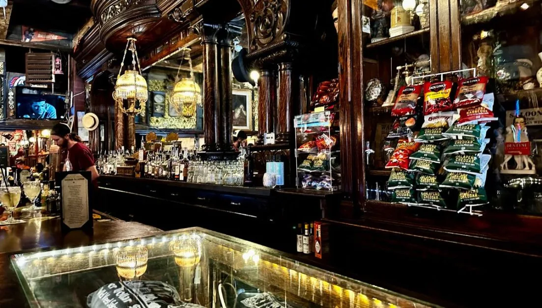 Inside of western saloon with original decor including mirrors and hanging lamps.