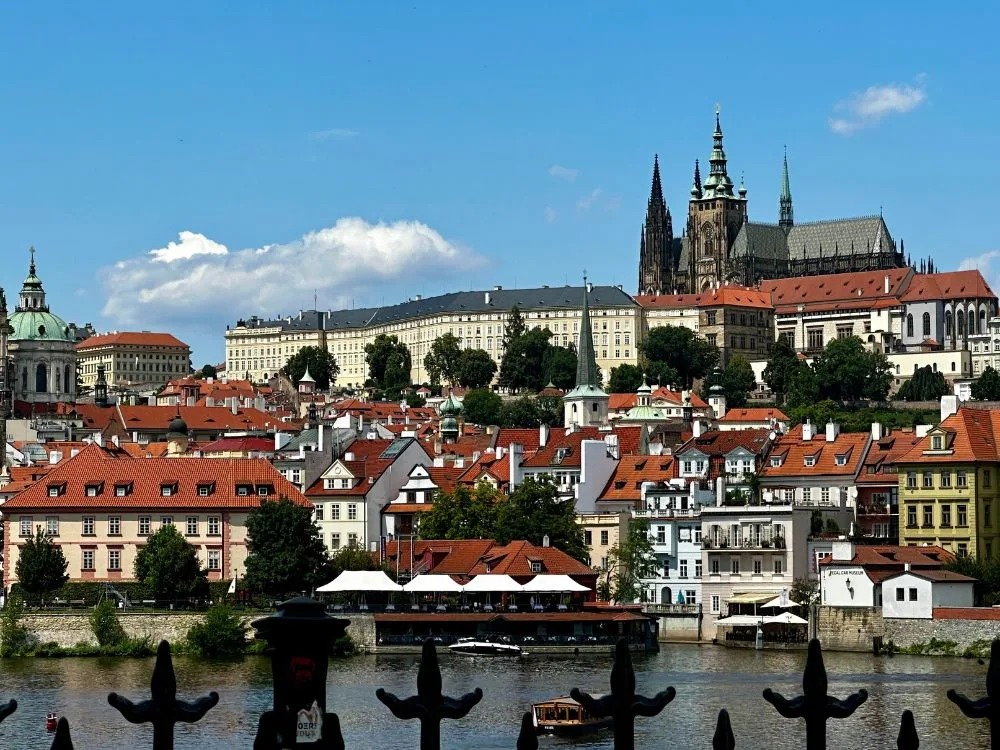 View of Prague city from river shows why Prague is worth visiting. Castle towers, medieval buildings flow down from the hillside to the river.