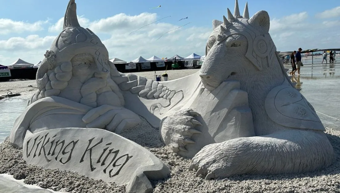 A sand sculpture on Siesta Key Beach Sarasota depicting figures from Viking era.  There are retail tents on the beach behind - all part of the annual Crystal Classic event.
