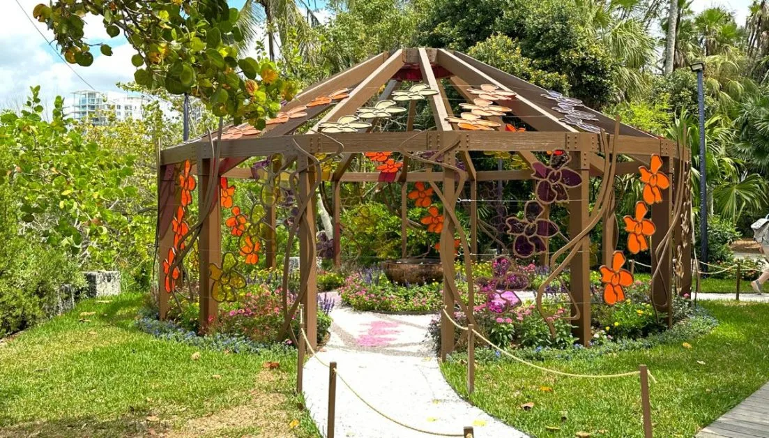 A steel pagoda decorated with flowers stands in Marie Selby Gardens surrounded by flowers and tropical plants. A visit to these gardens is one of the most popular things to do in Sarasota during a vacation.