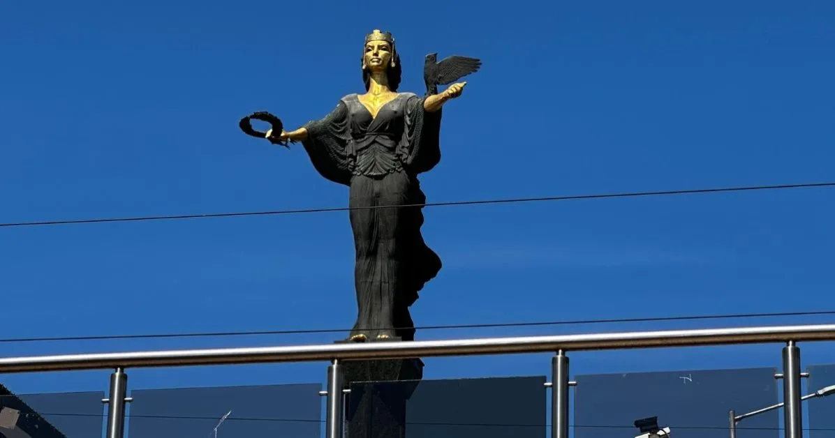 A monument of a woman - Sofia - the patron saint of the city. The statue is black with gold face and body. She has an owl in one hand and a wreath  in the other.