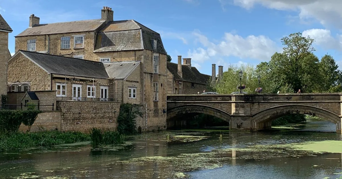 Stone buildings by th river with arched bridge and river flowing next to it