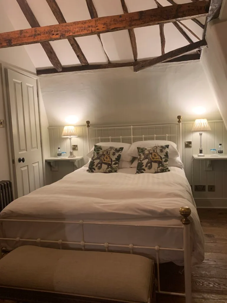 Interior bedroom of a hotel showing wood beams on the ceiling.