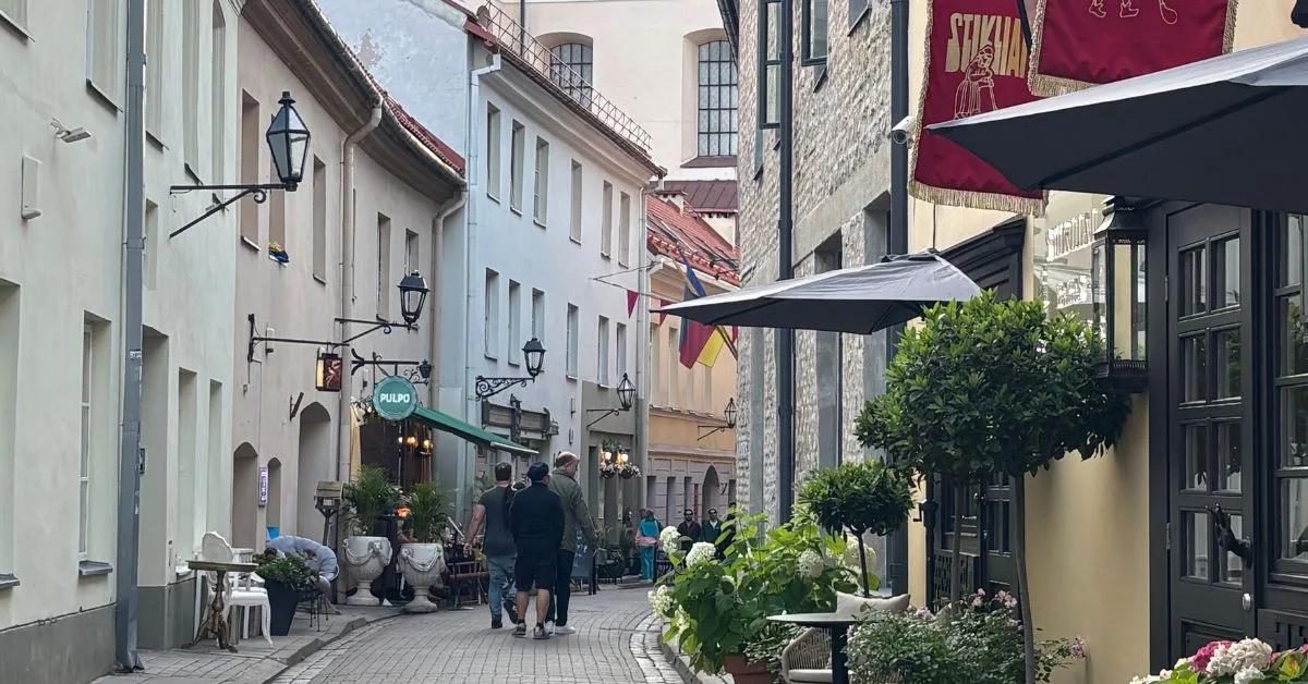 People walking along the narrow streets that are cobbled. Cafes at the side